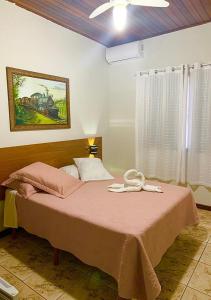 JacarèzinhoHotel Avenida的一间卧室配有一张带粉色毯子的床