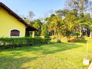 伊比乌纳Casa de Campo Lazer Completo Paraíso de Reservas Naturais em Sp的一座拥有黄色房子和树木的院子