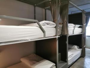 曼谷The Marble Hostel的客房设有三张双层床,配有白色床单