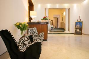 特拉帕尼阿尔贝戈鲁索酒店的大堂设有两把椅子和一张带鲜花的桌子