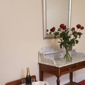 西埃勒河畔科尔德雷蒙七世酒店的一张桌子上的玫瑰花瓶和一瓶香槟