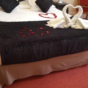 西埃勒河畔科尔德雷蒙七世酒店的一张床上有红玫瑰的黑色毯子