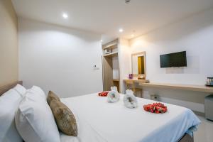 甲米镇瓦纳罗姆公寓式酒店的一间卧室配有白色的床铺、白色的枕头和电视