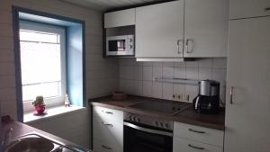 克林根塔尔Ferienwohnung Louise的厨房配有白色橱柜和炉灶烤箱。