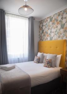 伦敦Paddington Park Hotel的一间卧室配有一张带黄色床头板的床和窗户