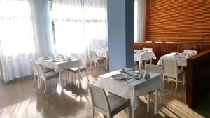 萨索斯玛丽酒店的用餐室配有白色的桌子和白色的椅子