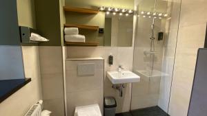 慕尼黑Munich Rooms Hotel的带淋浴、盥洗盆和镜子的浴室