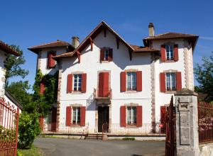 圣艾蒂安德拜戈里Maison Graciateguy的一间大型白色房屋,设有红色百叶窗