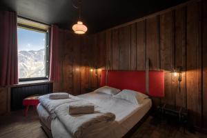 夏蒙尼-勃朗峰Refuge du Montenvers的一间卧室配有一张带红色床头板的床和窗户