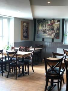 诺里奇Al Forno Restaurant & Inn的餐厅设有木桌和椅子,墙上挂有绘画作品
