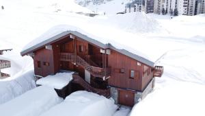 蒂涅Chalet Le Grand Cap的雪覆盖的建筑,有雪覆盖的楼梯
