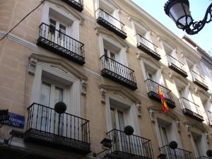 马德里普拉多套房酒店的带阳台的建筑,上面有国旗