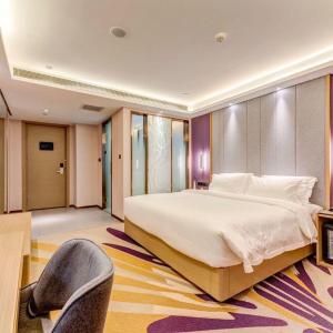 唐山Lavande Hotel Tangshan Convention and Exhibition Yuanyang City的一间卧室配有一张大床和一把椅子
