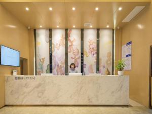 荆门Lavande Hotel Jingmen Planet World City的大堂设有墙上鲜花的前台台