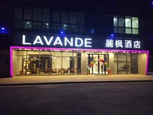 徐州Lavande Hotel Xuzhou New Town Midea Plaza的带有夜间读取乐凡达明标志的建筑物