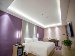 锦州Lavande Hotel Jinzhou Jiefang Road Kaixuan Building的卧室配有白色的床和紫色墙壁