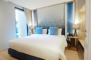 曼谷UHG The Quarter澎蓬酒店的卧室配有带蓝色枕头的大型白色床