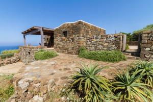 潘泰莱里亚Dammuso Kaddiuggia Antica Pantelleria的一座石头房子,位于一座小山上,背靠大海
