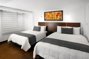 帕斯托Hotel Torre del Bosque Pasto的白色和黑色的酒店客房内的两张床