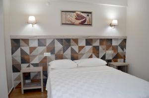 艾瓦勒克梅佳思酒店的卧室配有白色的床和几何墙