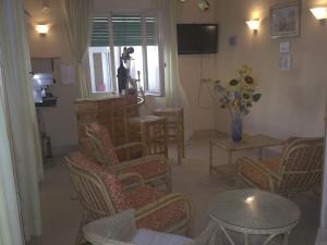 里米尼玛格达酒店的客厅配有椅子、桌子和电视