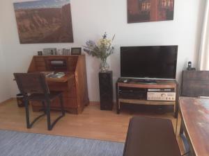 阿尔特瑙Ferienwohnung am Kunstberg 29的客厅配有电视和带桌子的书桌。