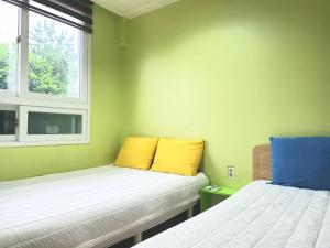 首尔汤米旅舍的配有两张黄色和蓝色枕头的床铺