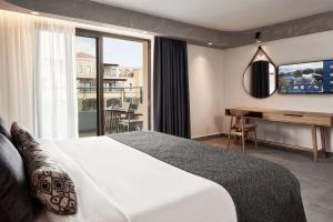 赫索尼索斯Atlantica Caldera Palace的配有一张床、一张书桌和一扇窗户的酒店客房