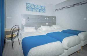 普瓦捷马克床酒店的一间卧室配有两张带蓝色床单的床和一张书桌