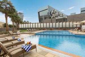 利雅德利雅得皇冠假日酒店 - RDC酒店与会议中心的一座带椅子的大型游泳池和一座建筑