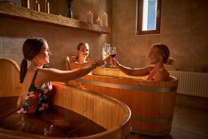 米库洛夫Hotel Ryzlink的三个妇女在热水浴缸中,拿着酒杯