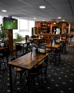 曼彻斯特曼彻斯特米尔顿酒店的一间带木桌椅的餐厅和一间酒吧