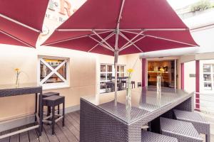 科隆科隆城弗瑞森斯塔德美居酒店的露台上配有大紫色雨伞的桌子