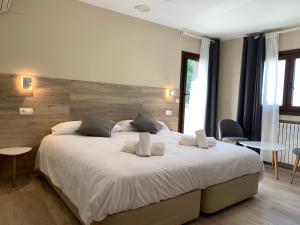 Plasencia del MonteHotel El Cobertizo的卧室配有一张带两个枕头的大白色床