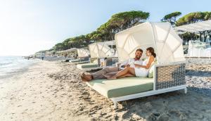 福洛尼卡The Sense Experience Resort的坐在海滩上床边的男人和女人