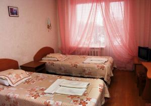 波尔塔瓦基辅酒店的客房设有两张床和一个带粉红色窗帘的窗户。