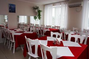 波尔塔瓦基辅酒店的餐厅设有红色和白色的桌子和白色的椅子