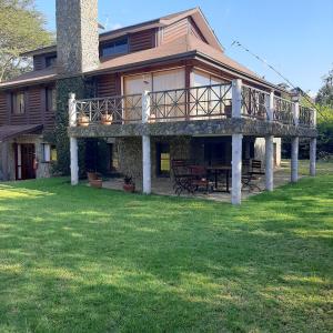 奈瓦沙Kwezi Cottage at The Great Rift Valley Lodge & Golf Resort Naivasha的草坪上带甲板的大房子