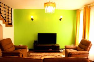 内罗毕Little Green Room Homestay near JKIA Airport & SGR Railway Station的绿色客厅配有2把椅子和平面电视