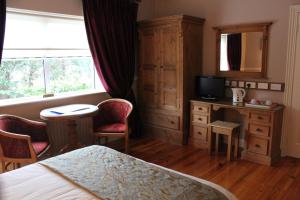 亚达尔阿黛尔乡间别墅酒店的一间卧室配有一张床、一张书桌和一台电视