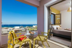 普拉基亚斯Sea View Luxury Apartments的客房设有阳台、一张床、一张桌子和椅子