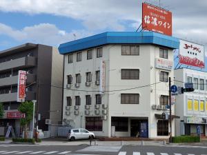 盐尻市Biz Hotel Shiojiri Ekimae的白色的建筑,蓝色的屋顶在街上