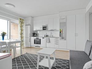 奥卢奥卢家居庭公寓的厨房配有白色橱柜和桌椅