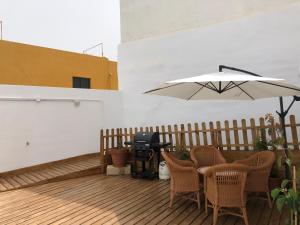 拉克鲁斯Punta Brava Relax的天井配有桌子、烧烤设施和雨伞。