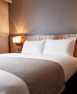 皇家伍顿巴西特The Churchill By Greene King Inns的卧室配有一张带白色床单和枕头的大床。