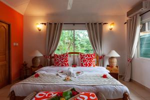 拉迪格岛海洋联合别墅的一间卧室配有两张带红白色枕头的床