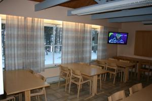 Lohijärvi荒野中心鲑鱼湖酒店的一间设有桌子的用餐室和墙上的电视
