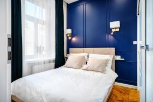 卢布林APARTAMENTY ARTE LUBLIN Niecała 11 parking free的一间卧室拥有蓝色的墙壁,配有一张带白色枕头的床。