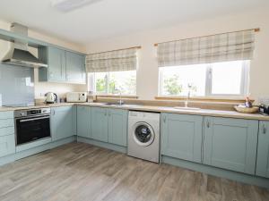 Powfoot2 Whiterow的厨房配有蓝色橱柜、洗衣机和烘干机