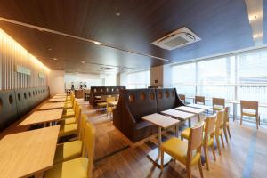 东京滨松町京王布莱索经济型酒店的餐厅设有木桌和黄色椅子